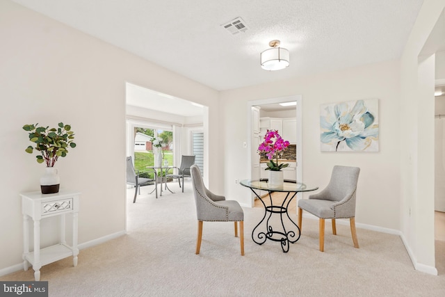 dining room featuring light colored carpet and baseboards