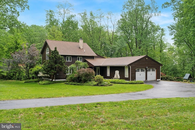 view of front of house with an attached garage, asphalt driveway, a front lawn, and a chimney