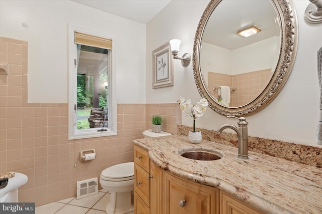 bathroom featuring tile patterned flooring, tile walls, toilet, a wainscoted wall, and vanity