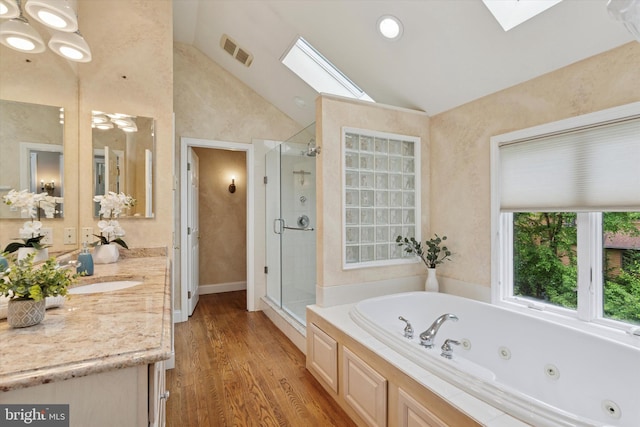 bathroom featuring a skylight, a stall shower, a whirlpool tub, lofted ceiling, and vanity