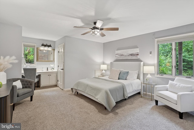 bedroom featuring light colored carpet, ensuite bathroom, a ceiling fan, and baseboards