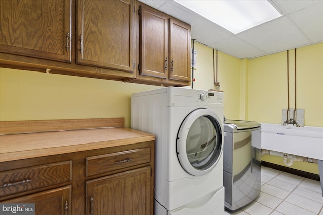 clothes washing area featuring cabinet space, washing machine and clothes dryer, and light tile patterned floors