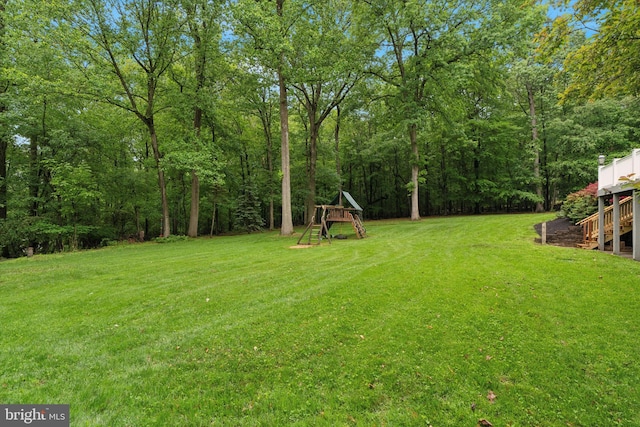 view of grassy yard with stairway and a wooded view