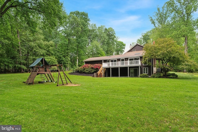 view of grassy yard featuring stairs, a playground, a deck, and cooling unit