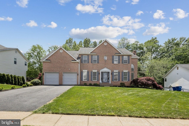 colonial inspired home featuring driveway, a front yard, brick siding, and a chimney
