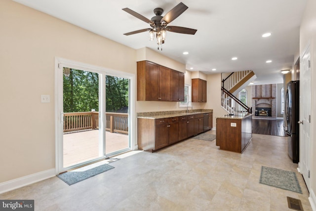 kitchen with freestanding refrigerator, a sink, light stone countertops, ceiling fan, and dishwashing machine