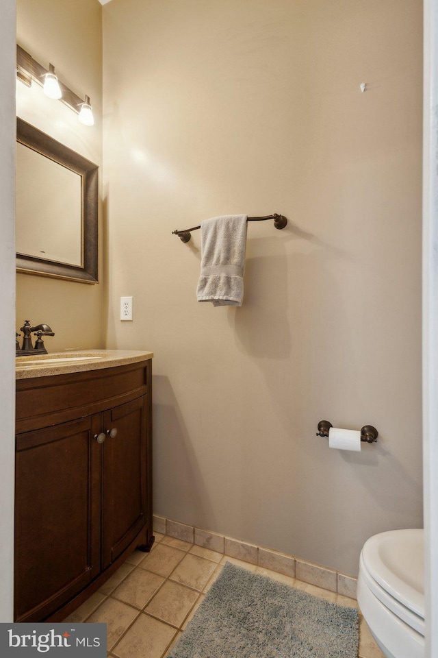 half bathroom featuring baseboards, toilet, and vanity