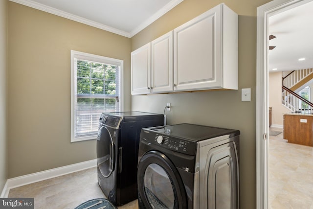 laundry area featuring washing machine and dryer, cabinet space, crown molding, and baseboards