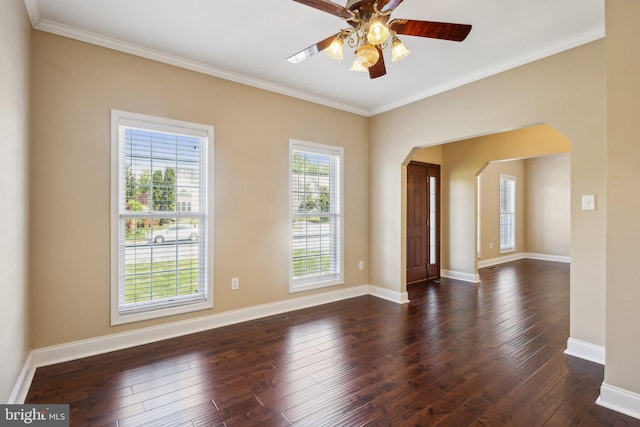unfurnished room featuring arched walkways, a ceiling fan, crown molding, dark wood-style floors, and baseboards