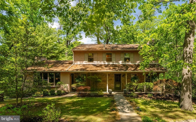 traditional-style house featuring stucco siding, a front lawn, a porch, and stone siding
