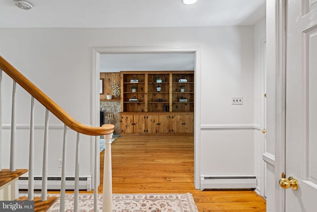 entryway with a baseboard heating unit, stairway, and wood finished floors