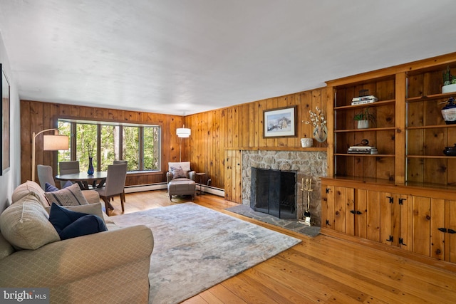 living room with a baseboard radiator, a fireplace, hardwood / wood-style floors, and wooden walls