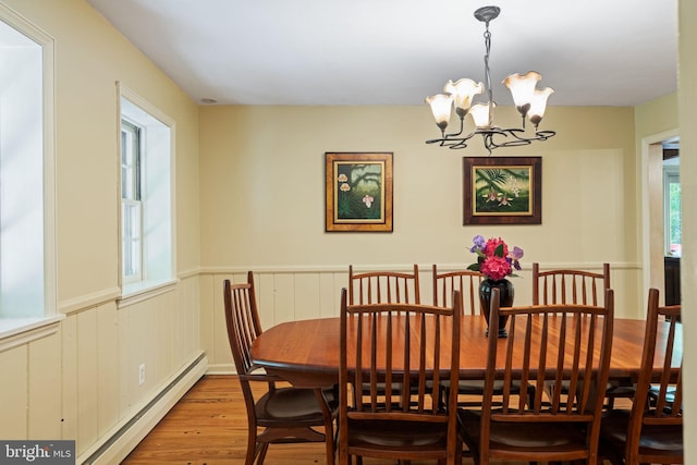 dining area featuring a baseboard radiator, wood finished floors, a chandelier, and wainscoting