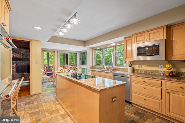 kitchen featuring appliances with stainless steel finishes, a sink, a center island, stone tile flooring, and recessed lighting