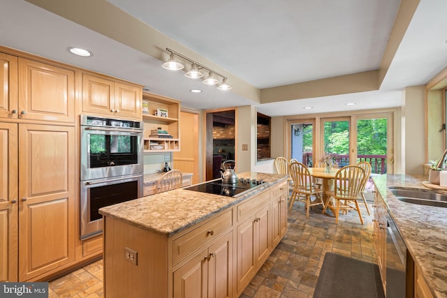 kitchen featuring appliances with stainless steel finishes, a sink, a center island, light stone countertops, and recessed lighting