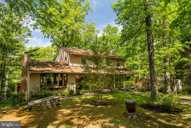 back of house featuring a chimney and stucco siding