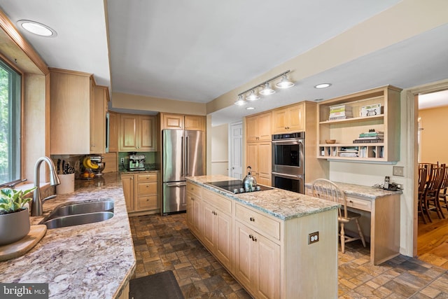 kitchen featuring stainless steel appliances, a sink, a center island, light stone countertops, and light brown cabinetry
