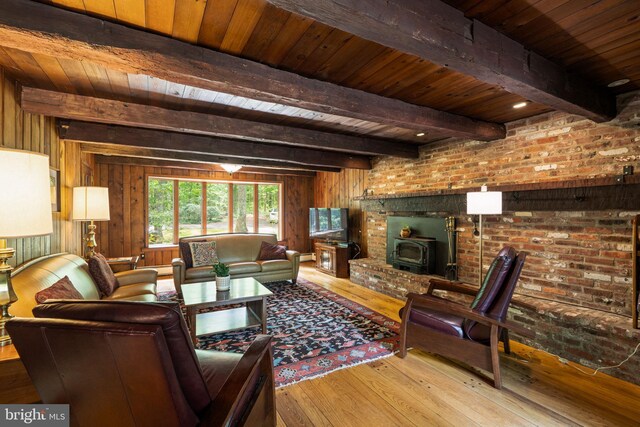 living room with wood ceiling, beamed ceiling, wooden walls, hardwood / wood-style floors, and a wood stove