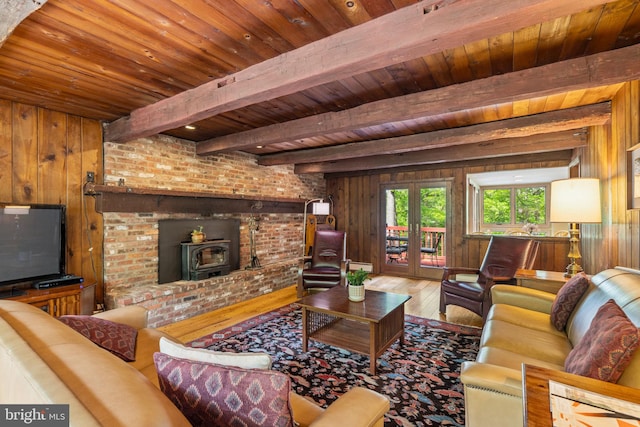 living room with wood ceiling, wood walls, hardwood / wood-style floors, a wood stove, and beam ceiling
