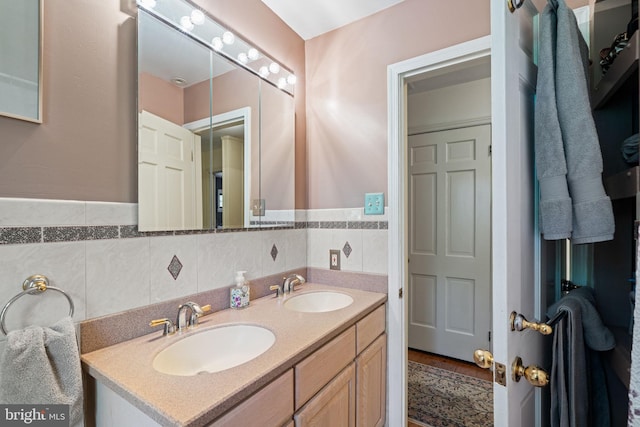 bathroom featuring double vanity, tile walls, and a wainscoted wall