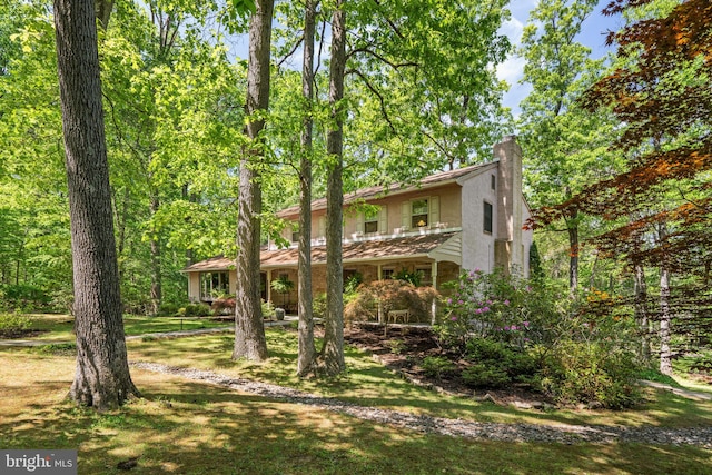 view of front of home with a chimney, stucco siding, and a front yard