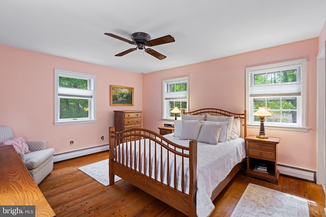 bedroom featuring a baseboard heating unit, hardwood / wood-style floors, and baseboards