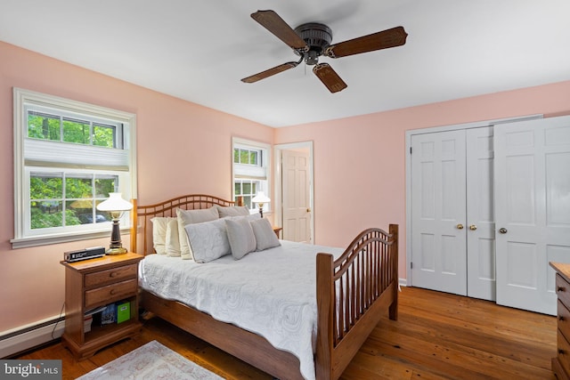 bedroom featuring wood-type flooring, a closet, ceiling fan, baseboards, and baseboard heating