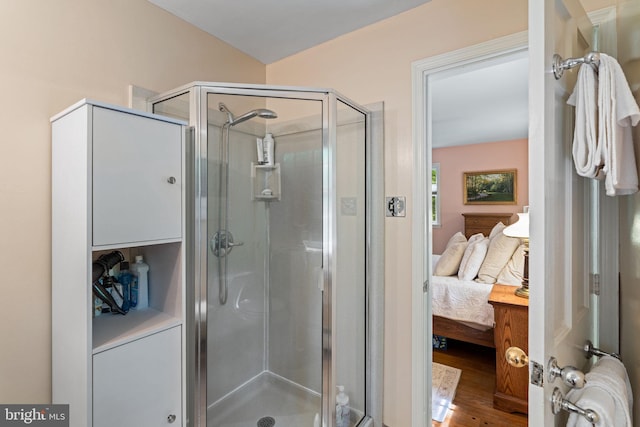 bathroom with ensuite bath, a shower stall, and wood finished floors