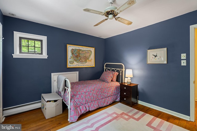 bedroom with baseboard heating, wood finished floors, baseboards, and ceiling fan