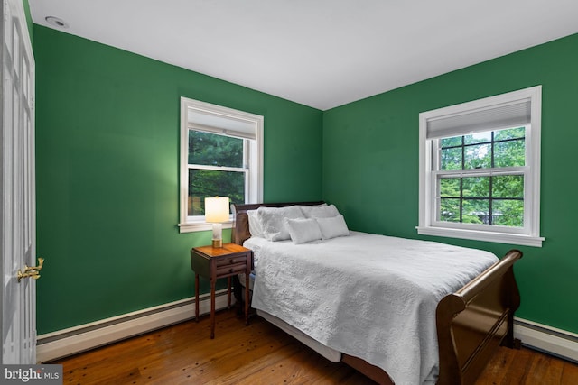 bedroom featuring a baseboard radiator, multiple windows, and baseboards