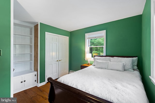 bedroom with dark wood finished floors, a closet, and baseboards