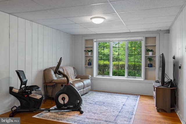 sitting room featuring wood finished floors, wood walls, and a drop ceiling