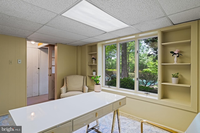 office space with built in shelves and a paneled ceiling