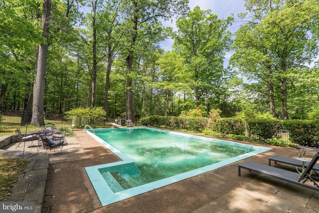 view of pool with a patio area, fence, and a diving board