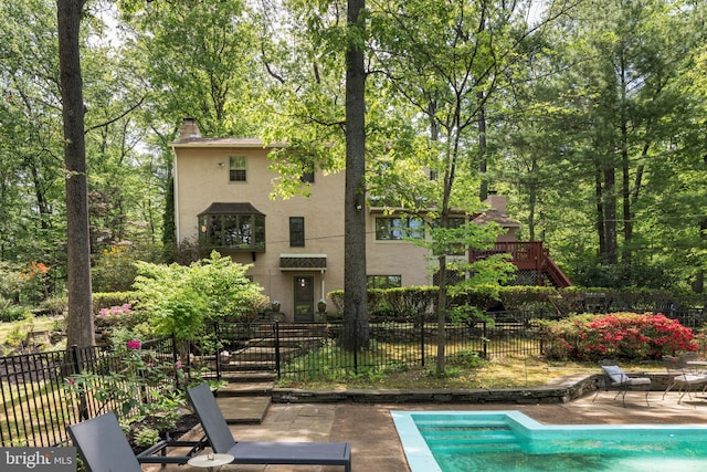 back of house with stucco siding, a patio, and a chimney