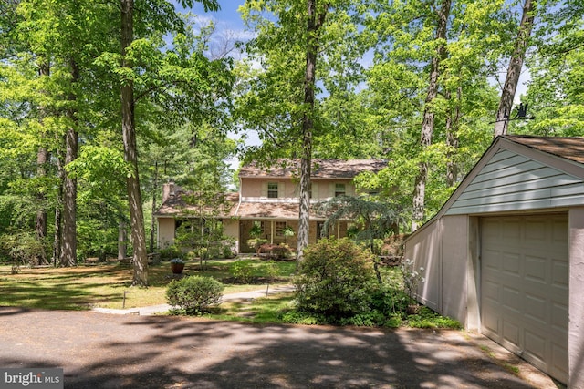 view of front facade with a chimney and asphalt driveway
