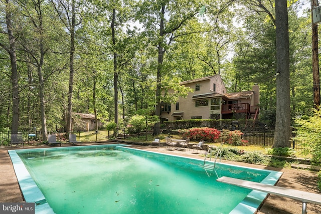 view of pool with a diving board and fence