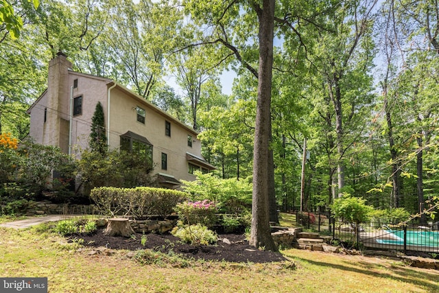view of home's exterior with stucco siding, fence, and a chimney