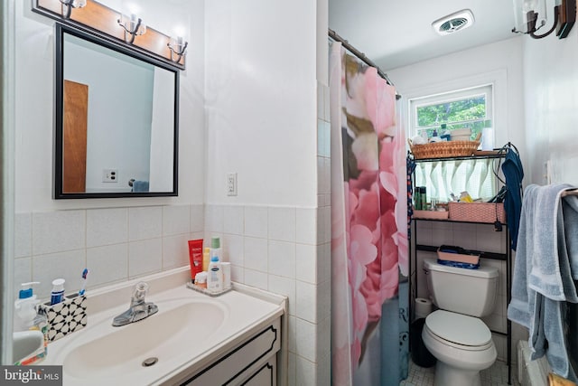 bathroom featuring tile walls, toilet, vanity, a shower with curtain, and wainscoting