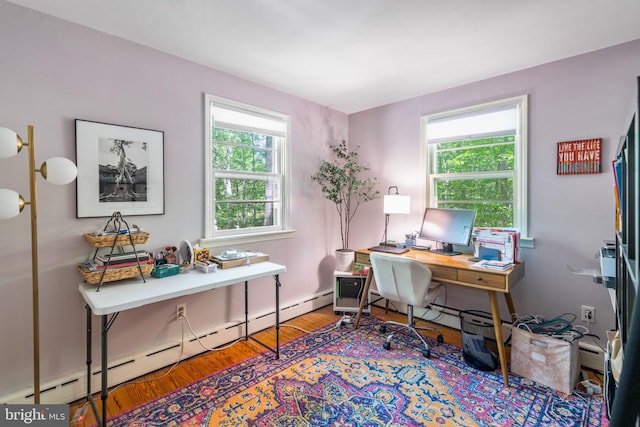 office space with a baseboard radiator, wood finished floors, plenty of natural light, and baseboard heating