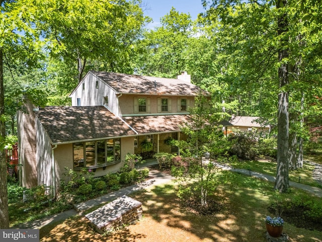 view of front of property featuring a chimney, stucco siding, and a shingled roof