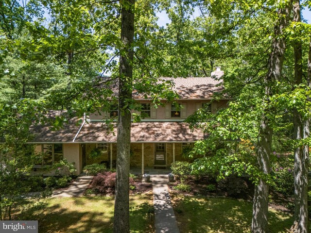 view of front facade featuring covered porch and a chimney