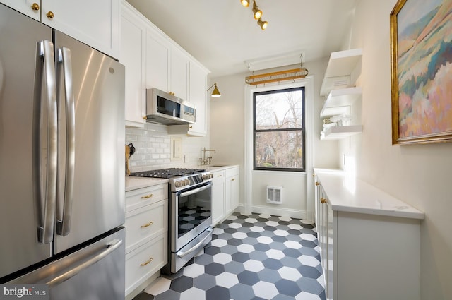 kitchen with appliances with stainless steel finishes, open shelves, dark floors, white cabinetry, and decorative backsplash