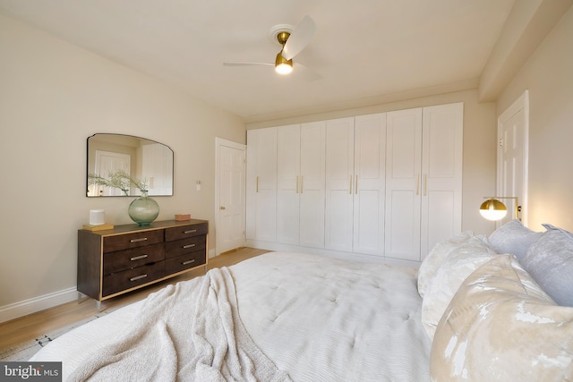 bedroom with light wood-type flooring, baseboards, a closet, and a ceiling fan