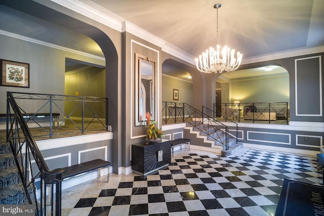 entrance foyer with arched walkways, a decorative wall, ornamental molding, a chandelier, and stairway