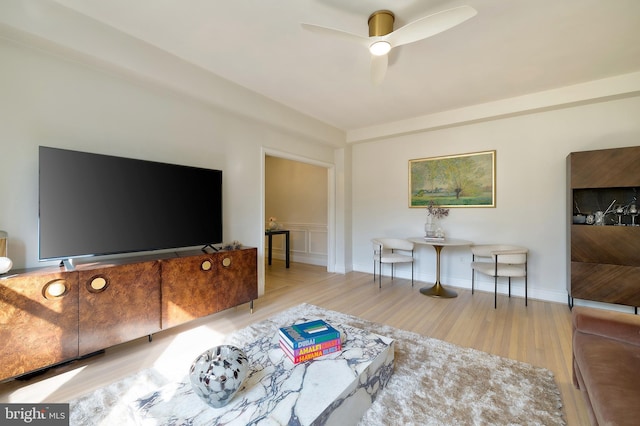 living area with a ceiling fan and wood finished floors