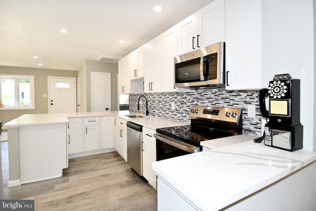1210 Lindsay Rd, Oxon Hill, MD 20745 - kitchen with a peninsula, appliances with stainless steel finishes, a sink, tasteful backsplash, and light wood finished floors