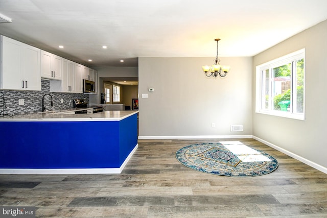 1210 Lindsay Rd, Oxon Hill, MD 20745 - kitchen featuring appliances with stainless steel finishes, wood finished floors, white cabinets, a peninsula, and baseboards