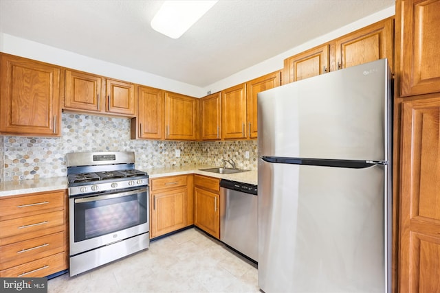 kitchen featuring appliances with stainless steel finishes, a sink, light countertops, and brown cabinets