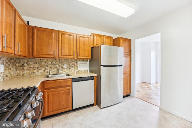 kitchen featuring appliances with stainless steel finishes, a sink, brown cabinets, and tasteful backsplash